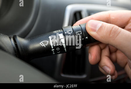 Macro photo of driver adjusting windscreen wipers control toggle Stock Photo