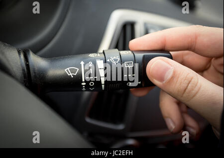 Closeup shot of male driver adjusting speed of screen wipers in car Stock Photo