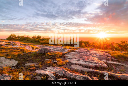 Sun sets over rocky granite outcroppings in early summer at top of New Jersey, High Point State Park Stock Photo