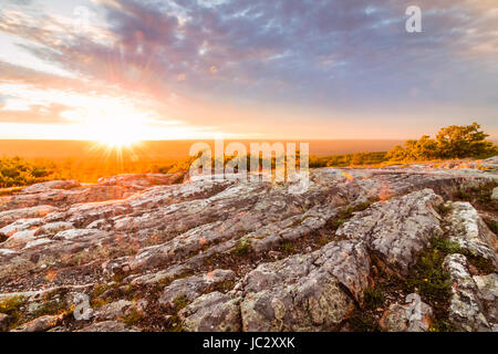 Sun sets over rocky granite outcroppings in early summer at top of New Jersey, High Point State Park Stock Photo