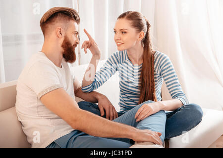 Happy young couple sitting together on sofa and looking at each other Stock Photo