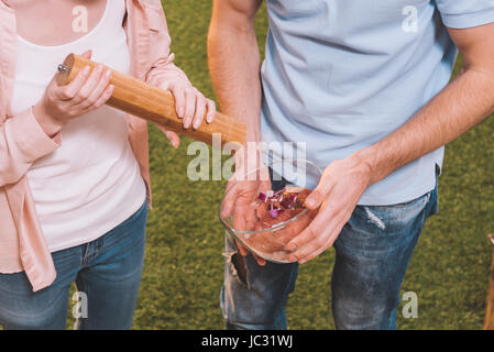 Close-up partial view of young couple pouring spices in meat for barbecue Stock Photo