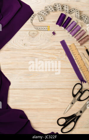 Sewing accessories on a light wooden background of purple and lilac colors. Selective focus. Stock Photo