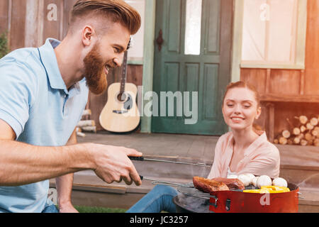 man and woman roasting meat and vegetables on barbecue grill Stock Photo