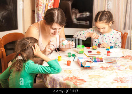 Portrait of mother with two daughters painting easter eggs Stock Photo