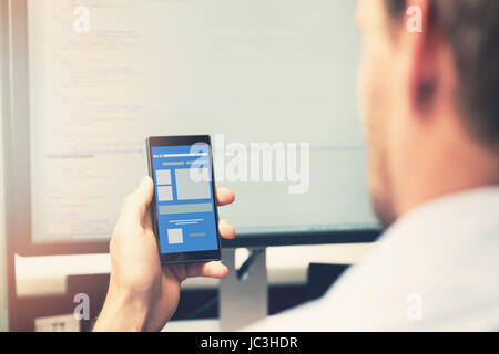 mobile app development - smart phone with application wireframe in programmer hand Stock Photo