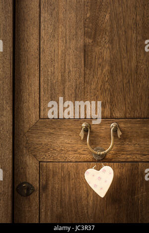 An old wooden door with a white heart hanging on its knocker Stock Photo