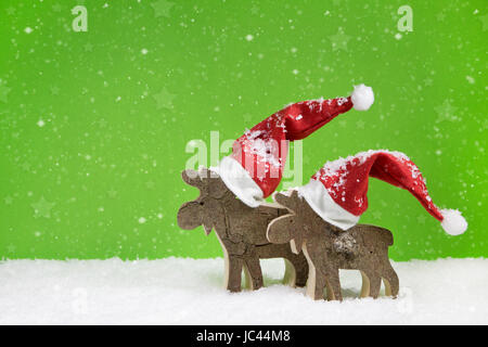 Two wooden handmade reindeer: funny green and white christmas background. Stock Photo
