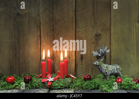 Classic: Four red burning christmas candles on wood background with deer. Stock Photo