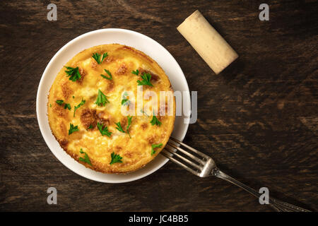 An overhead photo of the French quiche lorraine, typical pastry, on a dark rustic background with a place for text and a wine cork Stock Photo