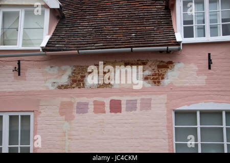 Pink Suffolk house wall prepared for painting with colour/color test  patches Stock Photo