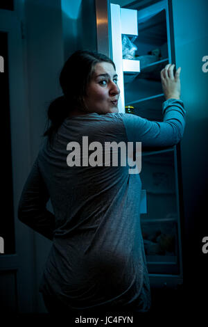 Photo at night of woman opening refrigerator Stock Photo