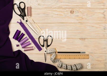 Sewing accessories on a light wooden background of purple and lilac colors. Selective focus. Stock Photo