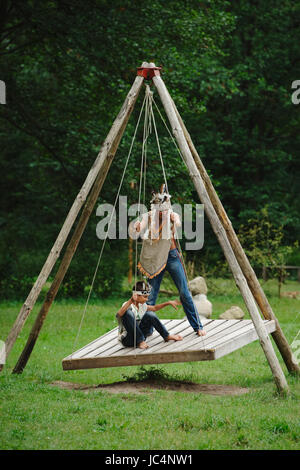 boys playing native american on swings Stock Photo