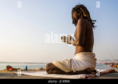 A Sadhu, holy man, is sitting and praying on a platform at the holy river Ganges at Meer Ghat in the suburb Godowlia Stock Photo