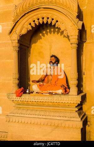 A priest, Brahmin, is sitting and praying on a balcony at the holy river Ganges at Lalita Ghat in the suburb Godowlia Stock Photo