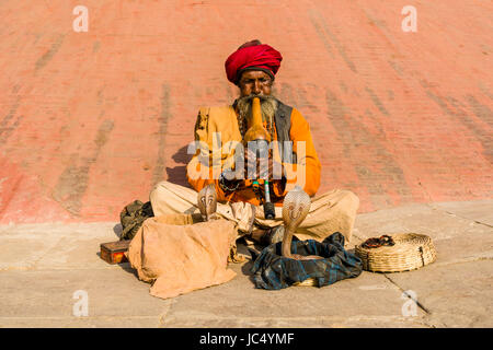 A snake charmer is playing flute to get his cobra dancing at the holy river Ganges at Dashashwamedh Ghat, Main Ghat, in the suburb Godowlia Stock Photo