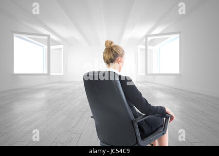 Composite image of blonde businesswoman sitting on swivel chair in black suit Stock Photo