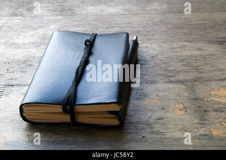 A leather bound journal sits on a table outside with a cord wrapped around the pages to keep place in book. Stock Photo