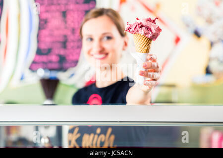 Ice-cream seller portion a scoop of ice cream to wafer in parlor counter or cafe Stock Photo