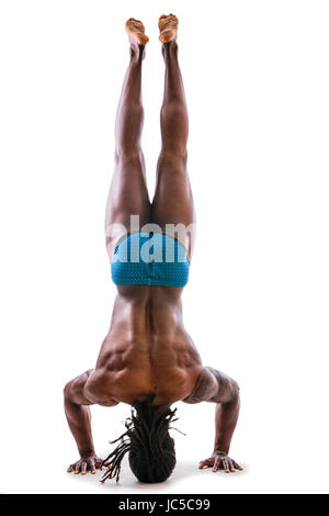 Black muscular man doing head-stand isolated against white background in studio Stock Photo