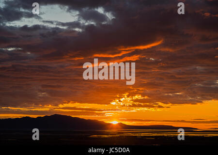 In this shot the sun lights up the bottom of the clouds as it sets over Antelope Island.  Antelope Island is the largest island in the Great Salt Lake Stock Photo