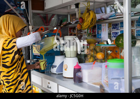 A woman making a fruit smoothie at her shop in Indonesia, Asia. Stock Photo