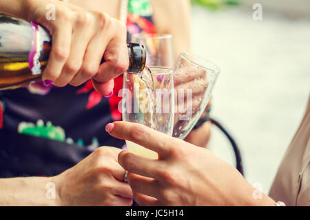Two girlfriends are drinking champagne in a city park. Joyful weekend. Stock Photo