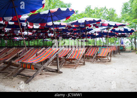 Lines of colorful beach chairs on sandy beach in Thailand Stock Photo