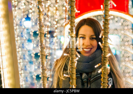 Young happy woman walking at night with christmas decorations. Beautiful tourist girl walking in busy city street Stock Photo