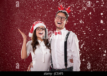 Happy nerd couple surrounded in snowflakes Stock Photo