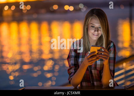 Pretty young girl using smart phone mobile in the city at night Stock Photo