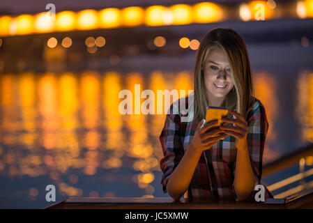 Pretty young girl using smart phone mobile in the city at night Stock Photo
