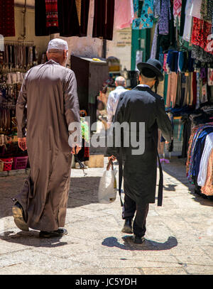 Street view of an old Arab man with prayer beads and a young Orthodox Jew lwith sidelocks carrying his shopping, Old City of Jerusalem, Israel. Stock Photo