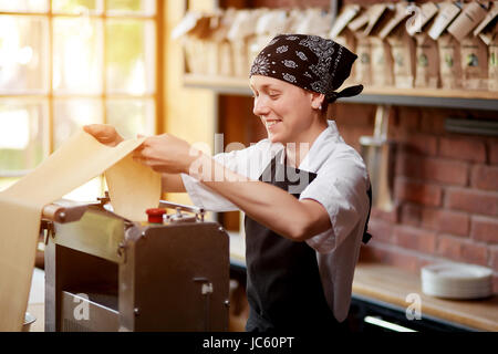 Smiling employee cooking pasta in restaurant Stock Photo
