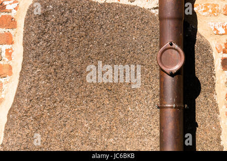 View of a red-brick exterior wall with brown drainpipe - for background purposes Stock Photo