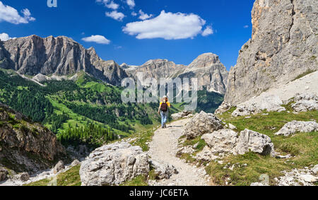 woman on footpath  in Sella mountain, on background Colfosco and Badia Valley, south Tyrol, Italy Stock Photo