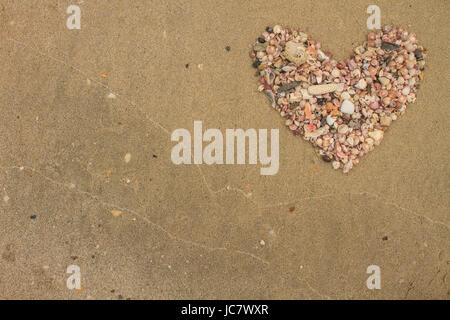 Heart made of sea shells lying on a beach sand in summer Stock Photo