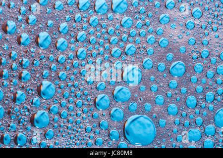 Water drops on glass with blue background, abstract rainy wallpaper Stock Photo