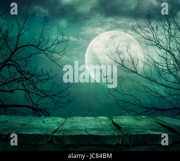 Halloween background. Spooky forest with full moon and wooden table Stock Photo
