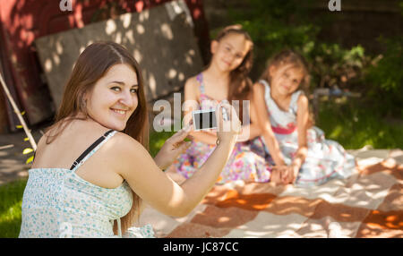 Beautiful smiling woman holding camera and making photo of daughters Stock Photo