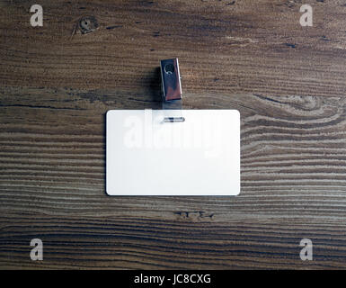 Photo of blank white plastic badge on vintage wooden table background. Blank id card. Top view. Stock Photo