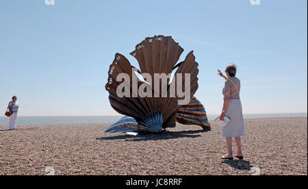 Aldeburgh Suffolk, UK. 14th June, 2017. Visitors enjoy the hot sunny weather and the famous Scallop sculpture by Maggi Hambling on Aldeburgh beach . Hot sunny weather is forecast to spread across Britain again in the next few days with temperatures reaching as high as 28 degrees in some parts Credit: Simon Dack/Alamy Live News Stock Photo