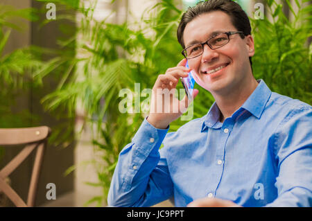 Attractive and handsome businessman using mobile phone, asian businessman having a phone talk, wealthy man talking on the smart phone seated in cafe a Stock Photo
