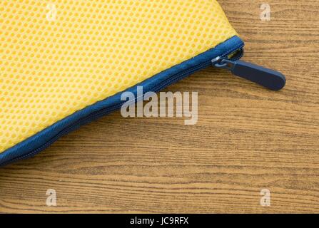 Yellow Pocket Bag and Blue Zipper on A Wooden Table. Stock Photo