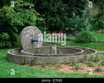 Old cider apple mill (cider press : granite stone and circular trough), public garden of Lassay les Châteaux (Mayenne, Loire country, France). Stock Photo