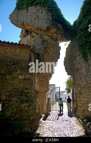 Alentejo, Portugal, 25-September-2007: A couple walking through a gate beneath a majestic clash of ancient ruins in Mertola village. Stock Photo