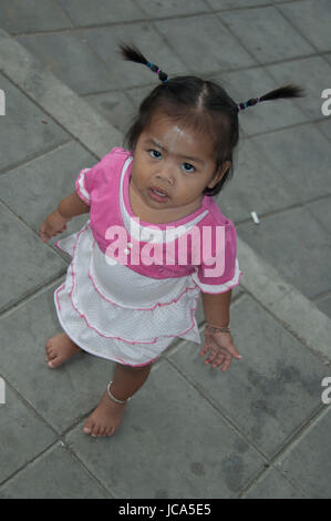 Bangkok, Thailand, 27-Oktober-2007: A street child with a smidge of chalk on her fore head is staring up at the photographer in Bangkok. Stock Photo