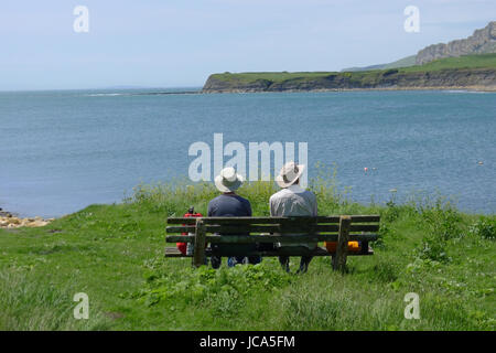 Cornwall, South England, 06-06-14: An old couple sitting on a bench and enjoying the view in Cornwall. Stock Photo