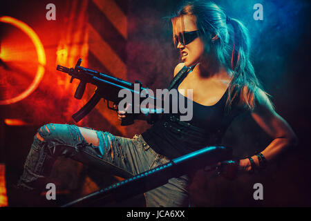 Young strong woman warrior with big guns in dramatic urban night scene Stock Photo